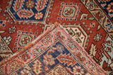 Corner of a vintage Heriz rug folded to show the brick red pile and hand-knotted foundation.