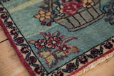 Corner detail of an antique Kerman mat's pictorial floral basket and meandering vine border.