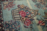 Angled view of the antique rug's pictorial basket of roses and floral sprays.