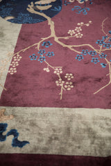 Close-up of the pictorial cherry blossom motif in blue and beige on a soft aubergine wool pile.