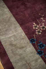 Oxidized silver tones on the border beside blue cherry blossoms on the soft aubergine wool pile.