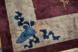 Corner detail of a stylized cloud band motif in cobalt blue on the lustrous silver wool pile.