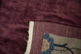 Corner view of the Art Deco carpet's hand-knotted foundation and deep aubergine pile.