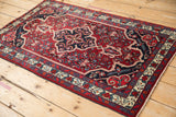 Angled view of a vintage Bijar rug showcasing its navy medallion against a red Herati design.