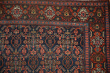 Vintage Persian Senneh rug corner, Herati design on navy field framed by brick red floral border.