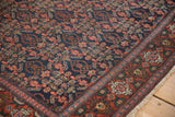 Corner detail of vintage Senneh rug, showcasing navy Herati field and brick red stylized guls border.