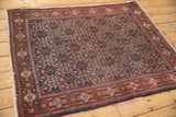 Vintage Senneh rug corner displaying brick red Samovar guls and navy Herati motifs.