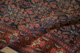 Textured close-up of Vintage Senneh rug, featuring intricate Herati and Samovar floral motifs in rich navy and brick red.