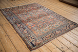 An angled view of the vintage Bibikabad rug with a terracotta tree of life pattern and navy blue border.