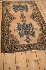 Corner of vintage Mehriban rug: ivory fringe, dark brown vine border, visible pile wear.