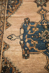 Textured close-up of vintage Mehriban rug's denim blue medallion and abrashed beige pile.