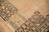 Vintage Tabriz rug corner showcasing coffee brown border with stylized palmette motifs and abrashed field.