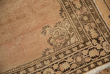 Vintage Tabriz rug corner: coffee brown floral border, dusty rose field, fringed end.