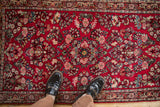 Overhead view of the dense floral bouquets on the cherry red field of a vintage Sarouk rug.