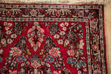 Close-up of a vintage Sarouk corner, showing the dense, short pile, floral patterns, and navy border.