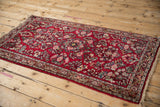 Vintage Sarouk rug featuring allover floral sprays on a cherry red field, shown from an angle.