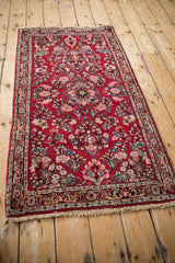 Angled view of a vintage Sarouk rug with floral spray bouquets covering its rich cherry red field.
