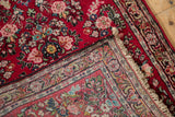 Folded corner of an American Sarouk rug revealing its cherry red floral pile and hand-knotted foundation.