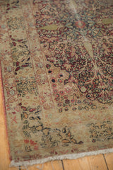 Worn fringe and aged floral patterns in cochineal red and antique ivory on an antique Kerman rug.