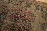Detail of antique Kerman rug's worn thousand flower motif with visible foundation.