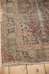 Antique Kerman rug with tattered fringe and worn floral border in cochineal red.