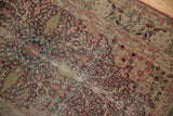 Antique Kerman rug detail: cochineal red thousand flower motif, navy accents, foundation wear.