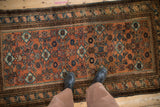 Vintage Malayer rug's terracotta and blue Herati design, showing even pile wear underfoot.
