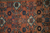 Close-up of vintage Malayer rug's Herati design with abrashes in terracotta and sapphire blue.