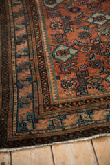 Vintage Malayer rug corner displaying terracotta field, blue Herati motif, and geometric borders.