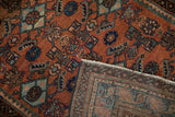 Vintage Malayer rug's flipped corner, showing terracotta Herati pattern, vivid blues, and striped back.