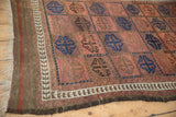 Hand-knotted antique Belouch rug corner, with primitive vine border and ram's horn gul motifs.
