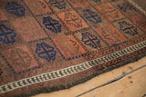 Detail of antique Belouch rug with madder red and cobalt ram's horn guls, vine border, and original selvage.