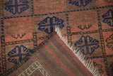 Antique Belouch rug's folded corner reveals blue guls, textured red pile, and striped foundation.