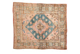 A vintage Anatolian square rug with a teal stepped medallion on a dusty rose field and floral vine borders.