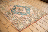Angled view of a vintage Anatolian rug showing the wide floral border and stepped corner spandrel.