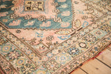 Stepped contour of the teal corner spandrel beside the rug's wide floral main border.