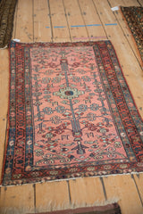 Angled view of vintage Persian Mehriban rug with dusty raspberry field, tree-of-life, and blue borders.