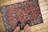 Vintage Persian Tajabad rug with a complex Herati pattern shown for scale on a floor.