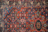 The detailed Serbend main border and gem-toned Herati field of a vintage Persian rug.