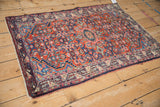 Angled view of a vintage Tajabad rug with a ruby red Herati field and dark Serbend border.
