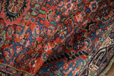 Angled view of a vintage Tajabad rug's even, short pile and dense Herati pattern in red and blue.