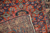 A folded corner of the vintage Persian rug shows the dense, colorful front pile over its hand-knotted back.