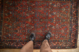 A personal perspective showing the scale and low-pile texture of the antique Bijar rug's Herati pattern.