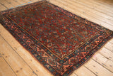 Angled view of an antique Bijar rug, highlighting its dense Herati pattern and detailed border.