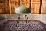 Collectible Seafoam Green Herman Miller chair with black X base, on a traditional patterned rug.
