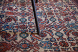 Black X base chair leg on a vintage rug with rust and blue floral motifs.