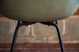 Close-up of textured seafoam green Herman Miller seat and large shock mounts on black X base.