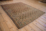 Vintage Sarouk rug corner with navy selvage, terracotta guard band, and intricate floral main border.