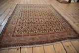Vintage Sarouk rug corner: terracotta and blue floral border with intact fringe.