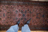 A detailed view of the antique Lilihan rug's dusty raspberry field with indigo blue sprawling vines.
